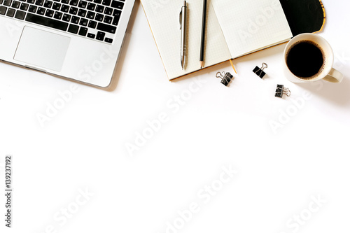 Modern minimalistic work place. White office desk table with laptop, coffee cup, clips, notebook, pen and pencil. Top view with copy space, flat lay