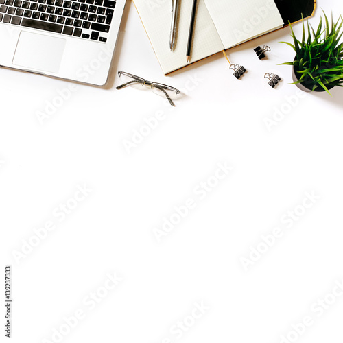 Modern minimalistic work place. White office desk table with laptop, clips, glasses, office plant, notebook, pen and pencil. Top view with copy space, flat lay