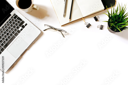 Modern minimalistic work place. White office desk table with laptop, coffee cup, clips, glasses, office plant, notebook, pen and pencil. Top view with copy space, flat lay