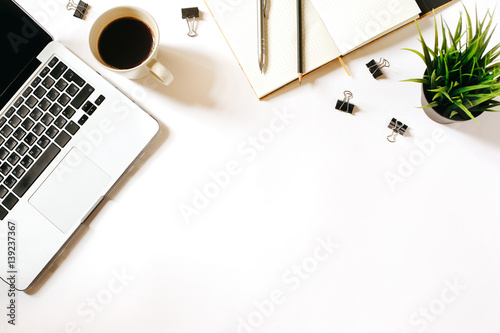 Modern minimalistic work place. White office desk table with laptop, coffee cup, clips, notebook, pen and penclil. Top view with copy space, flat lay