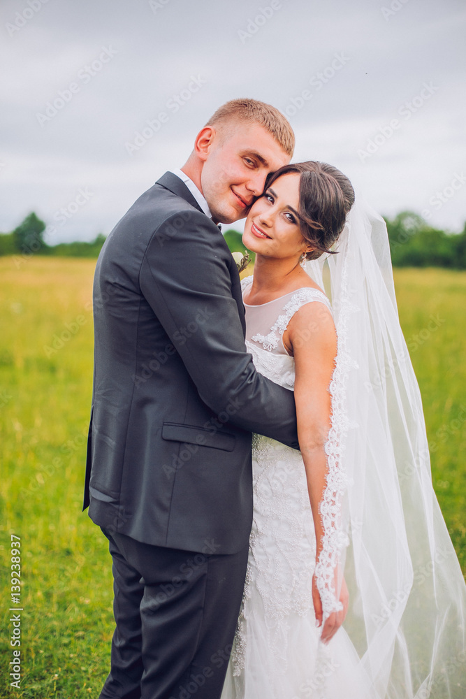 Wedding couple bride and groom on field background walking and embracing. Wedding couple bride and groom on field background walking and embracing.