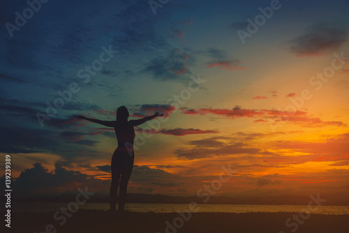Silhouette happy woman on the beach at sunset. Vintage tone
