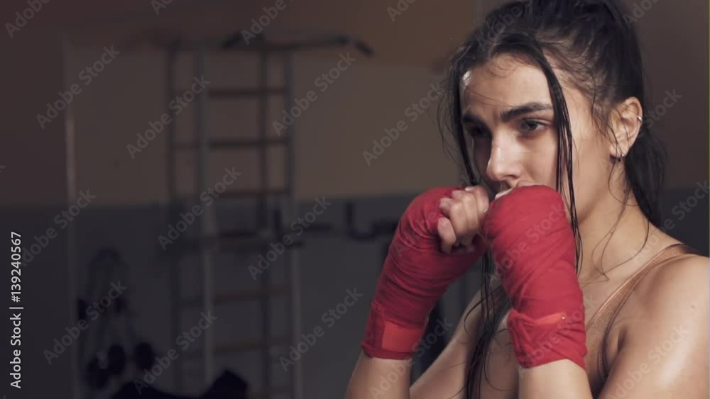 Beautiful girl in boxing gloves pushes the bag on a black background. Slow motion. Beautiful girl in boxing gloves pushes the bag on a black background. Slow motion.
