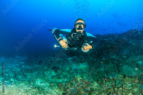 Female SCUBA diver using a techical side mount system on a deep coral reef © whitcomberd