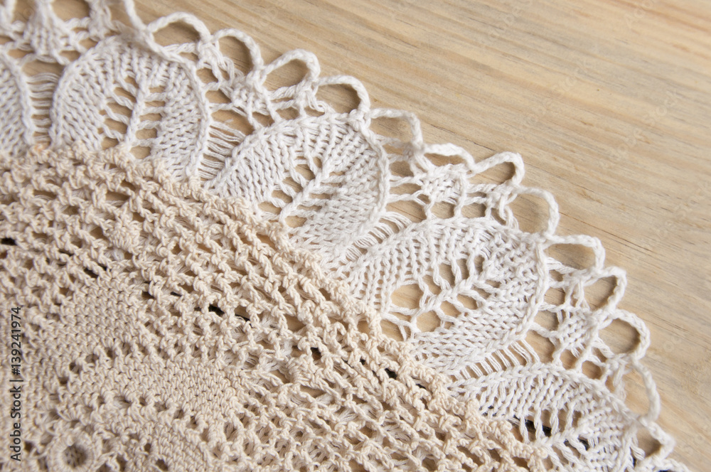 Obraz premium Knitted homemade white lacy doily on wooden background.