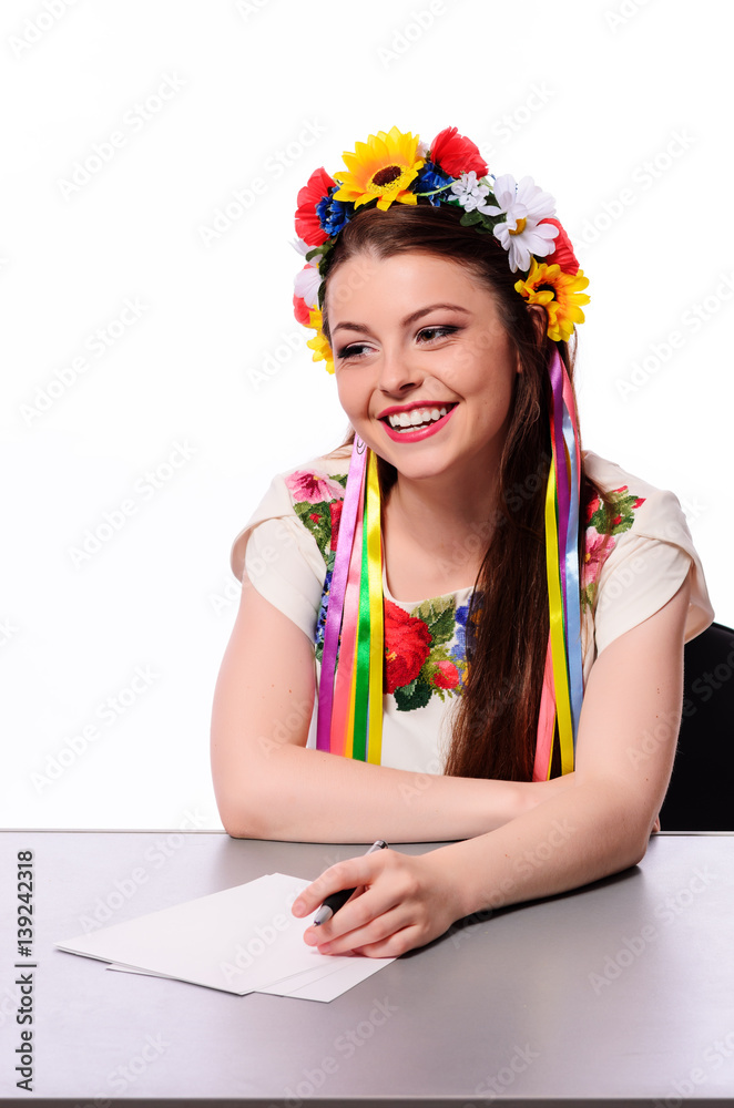 Happy businesswoman with note and pen by a desk.In the Ukrainian national costume Happy businesswoman with note and pen by a desk.In the Ukrainian national costume