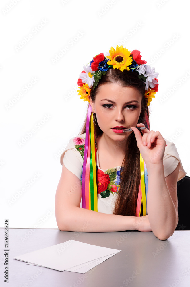 Happy businesswoman with note and pen by a desk.In the Ukrainian national costume