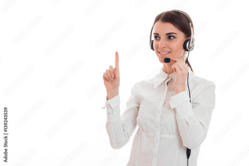 young girl in white shirt and headphones with microphone looks away and raised a finger up young girl in white shirt and headphones with microphone looks away and raised a finger up