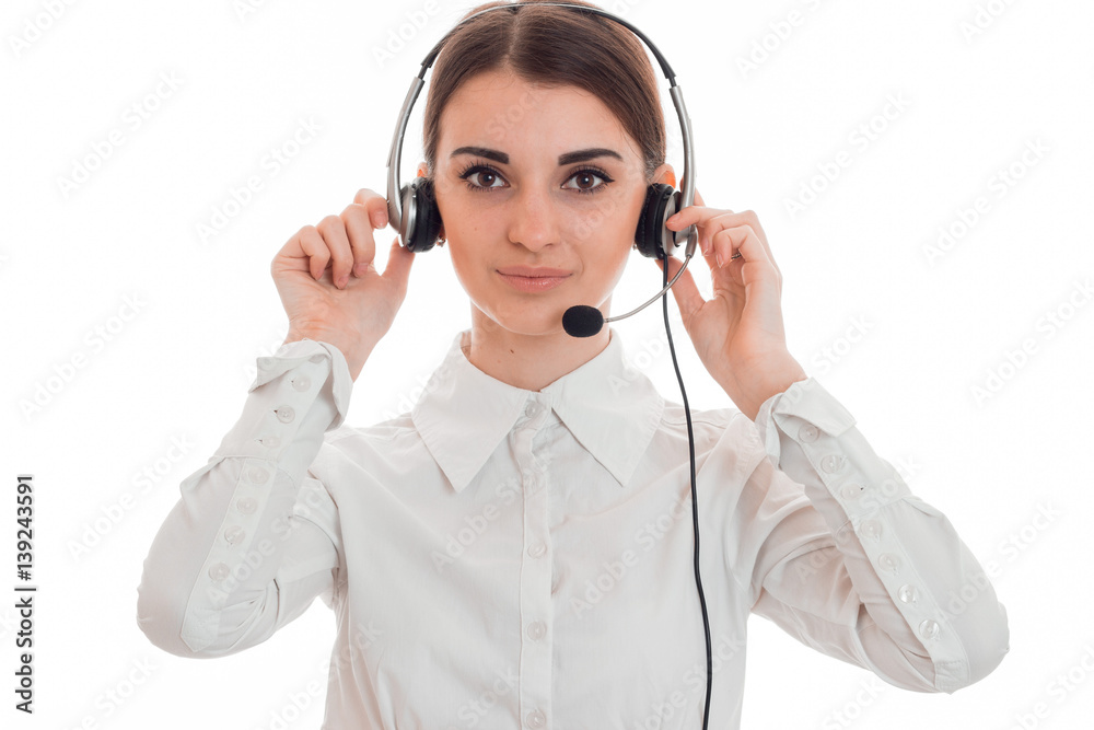 young girl in white shirt and headphones with microphone looks into the camera and holds the hands near head young girl in white shirt and headphones with microphone looks into the camera and holds the hands near head