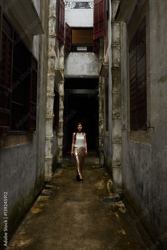Young woman walking down narrow alley between buildings Young woman walking down narrow alley between buildings