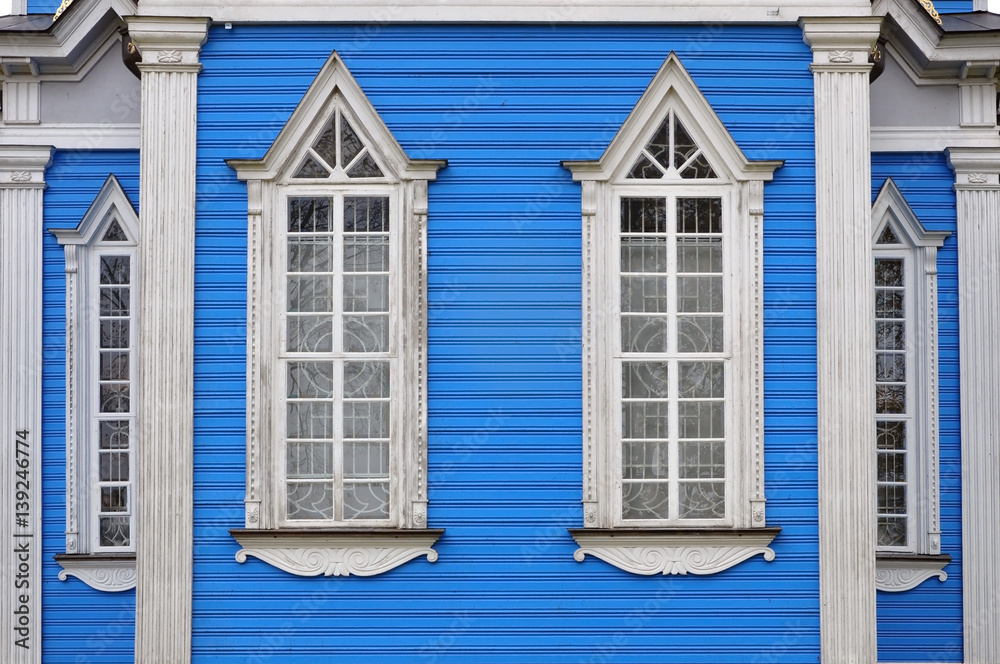Two decorative white wooden windows on a blue background. Ancient Orthodox Church in Druskininkai, Lithuania. Two decorative white wooden windows on a blue background. Ancient Orthodox Church in Druskininkai, Lithuania.