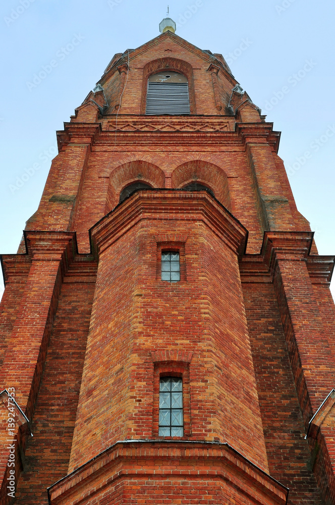 Tower of Gothic Church of the Holy Apostles Peter and Paul of red brick in the village Old Vasilishki, Grodno region, Belarus. Look up.