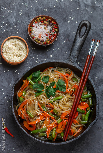 Spicy rice (potato) noodles with vegetables - carrots, bell peppers, green beans, ginger, and sesame seeds. Traditional popular dish of Asian cuisine. Cellophane, glass noodle. Selective focus