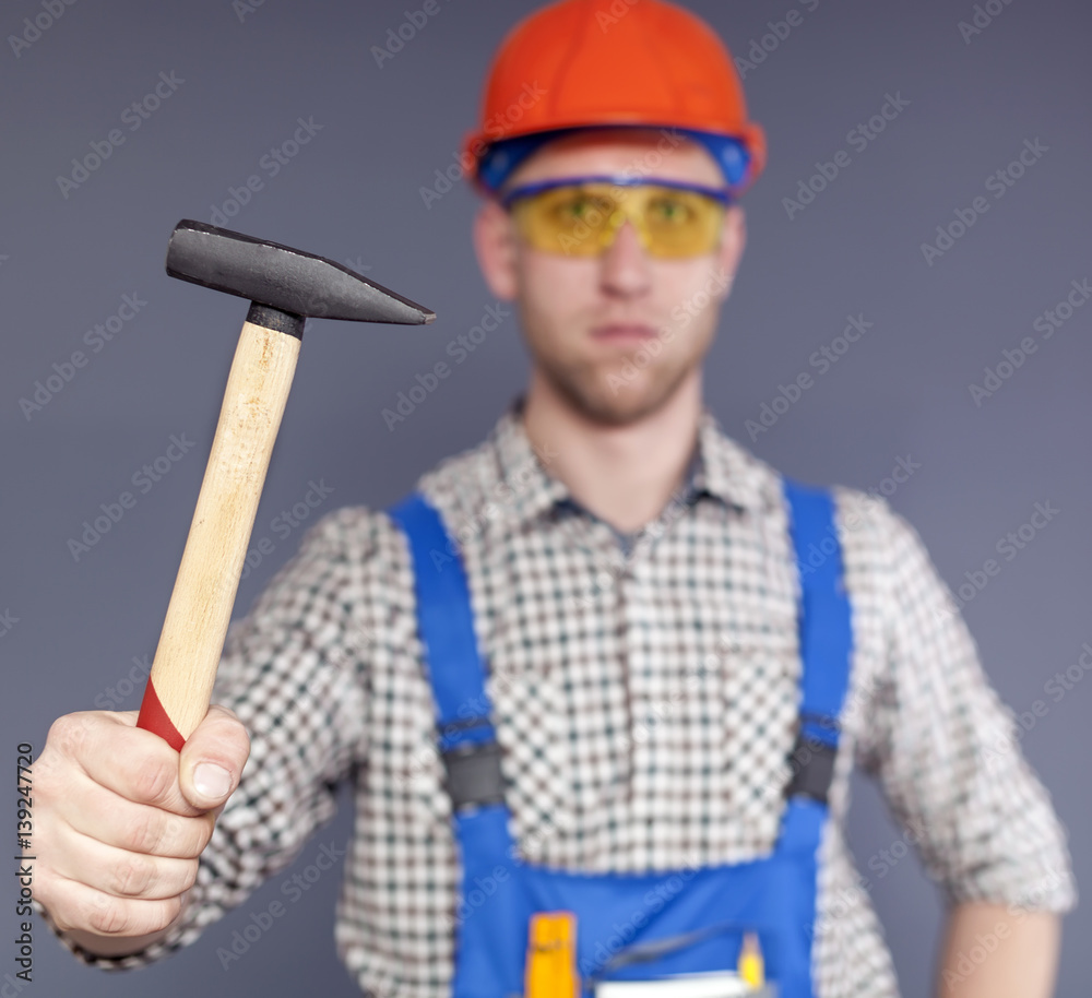 Hammer and serios blurred figure of worker in uniform Hammer and serios blurred figure of worker in uniform