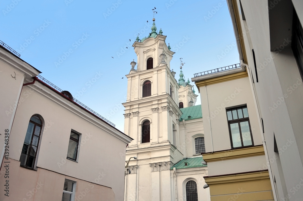 White tower of the Jesuit church in Baroque style among historic buildings. Grodno, Belarus.