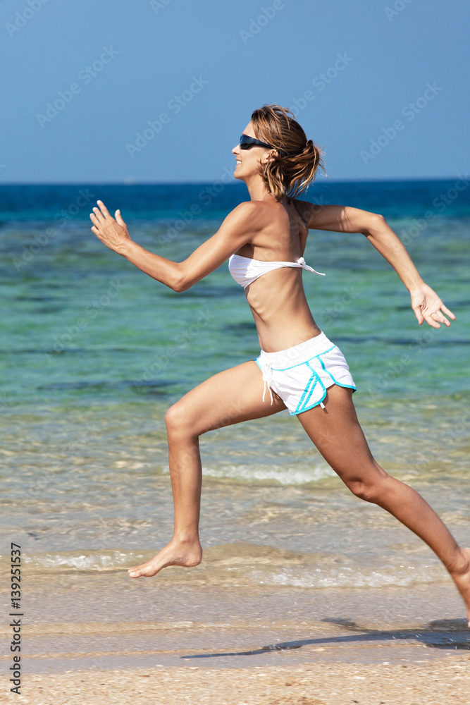 femme souriant qui court sur une belle plage