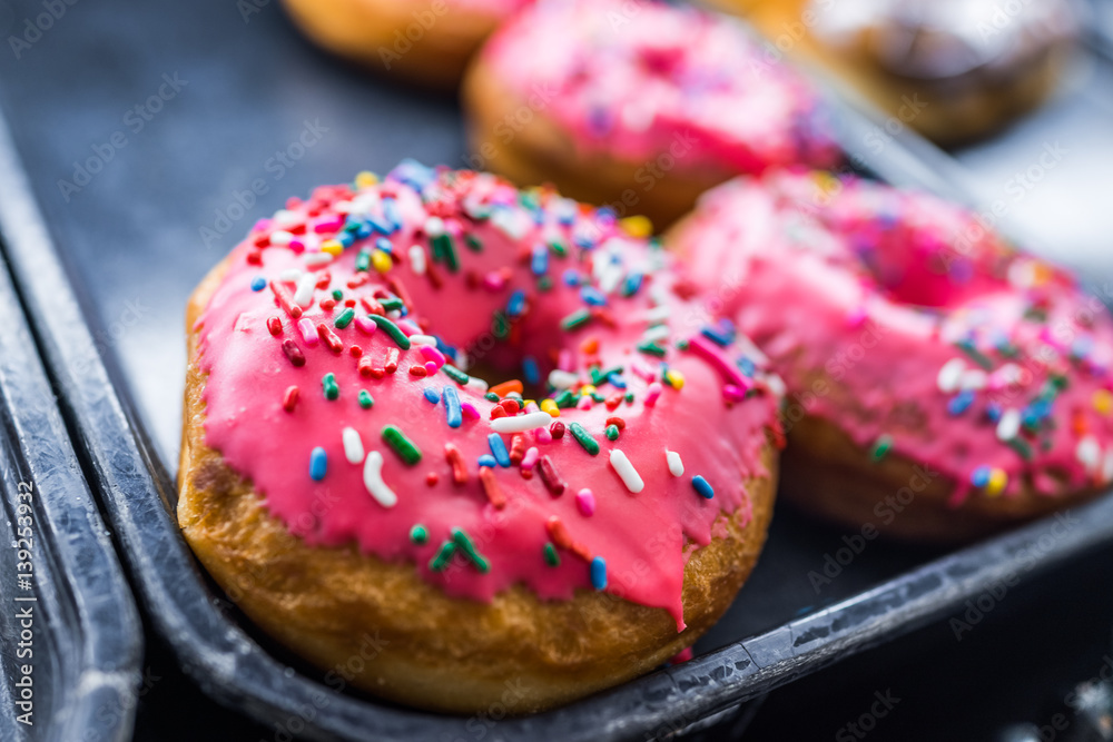 Fotografie Pink iced donuts with rainbow sprinkles