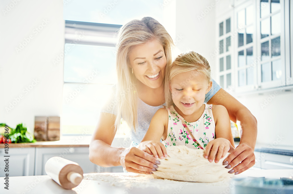 Pretty little girl kneading dough with her mother Pretty little girl kneading dough with her mother