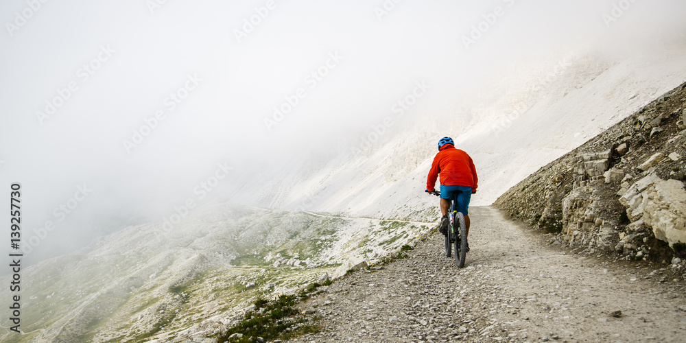 View of cyclist riding mountain bike on trail in Dolomites,Tre Cime di Laverado, South Tirol, Italy