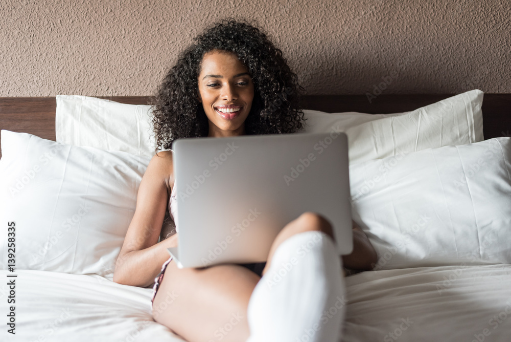 woman smiling drinking a coffee and working with her computer on bed woman smiling drinking a coffee and working with her computer on bed