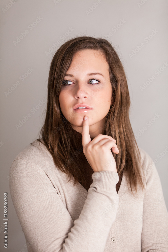 Thoughtful young brunette girl posing with finger under her chin Thoughtful young brunette girl posing with finger under her chin