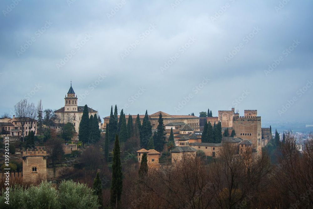 GRANADA, SPAIN - FEBRUARY 10, 2015: An iconic view of famous palace and fortress Alhambra at Granada, Andalusia, Spain, On cloudy rainy winter day.