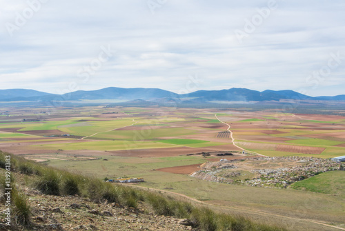 A view from a hill to fields, farms and mountains near Consuegra town at spring cloudy day. © Victoria