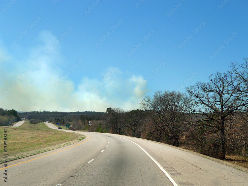Wildfire, grass fire, forest fire in the distance, smoke billowing, dangerous conditions, natural  disaster