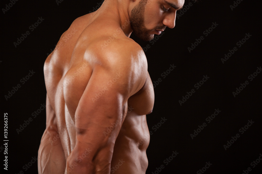 Strong Athletic Man - Fitness Model showing his perfect back isolated on black background with copyspace Strong Athletic Man - Fitness Model showing his perfect back isolated on black background with copyspace