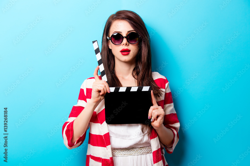 Naklejka premium beautiful young woman with cinema clapper standing in front of wonderful blue background