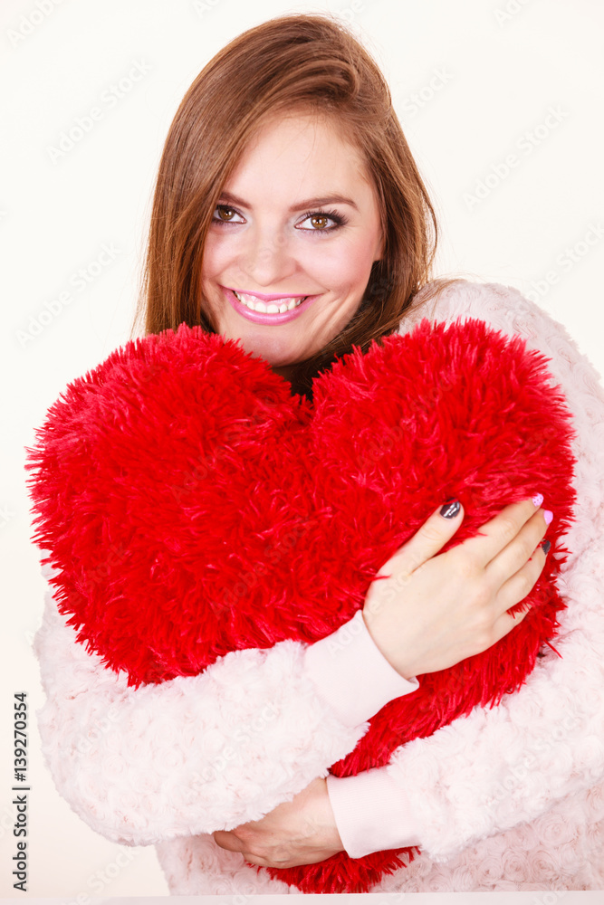 Happy woman holding heart shaped pillow Happy woman holding heart shaped pillow