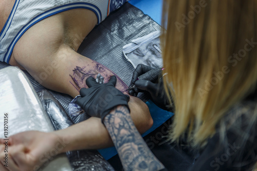 A tattoo artist is designing a tattoo on the arm of a client