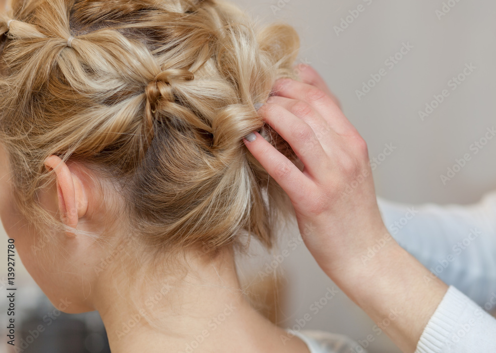 Naklejka premium Beautiful blonde girl with a beautiful, neat hairstyle, close-up in a beauty salon. Professional hair care and creating hairstyles.