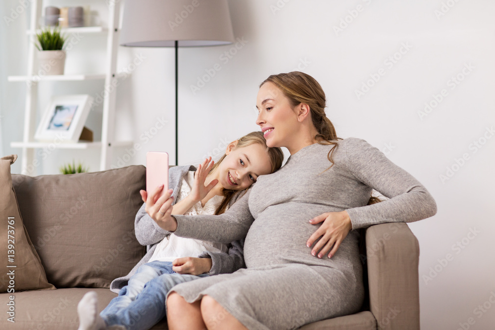 pregnant woman and girl taking smartphone selfie