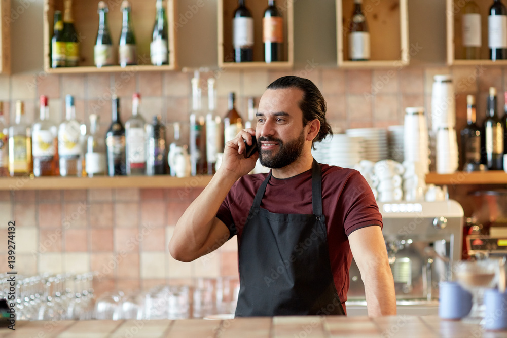 happy man or waiter at bar calling on smartphone