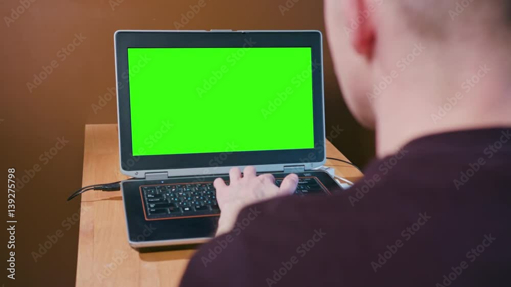 husband in home working on the computer with a green screen so you can substitute what you need husband in home working on the computer with a green screen so you can substitute what you need
