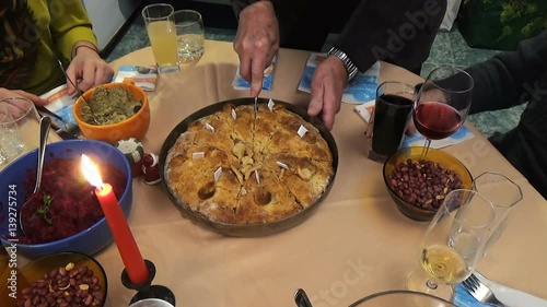 Family around Christmas Eve dinner table. The grandfather breaks the bread with fortunes traditional way of celebrating the Christmas Eve. Candle lit on the table gives warmth and romance feeling.