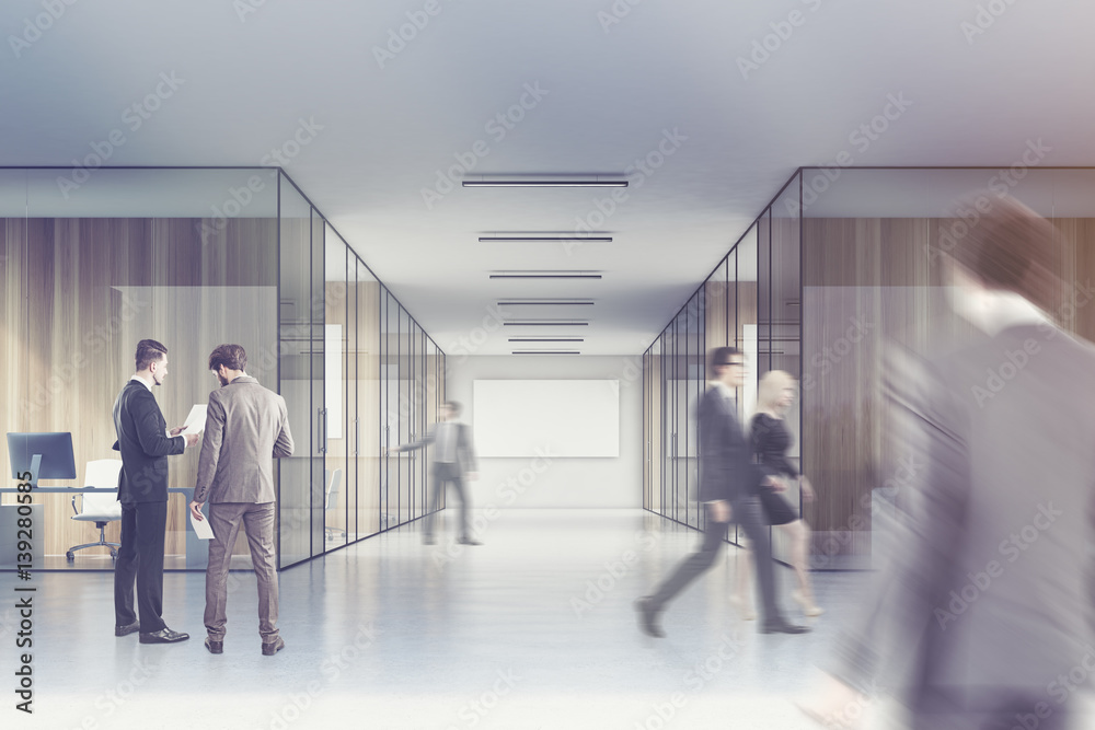 People in a long office corridor with a poster People in a long office corridor with a poster