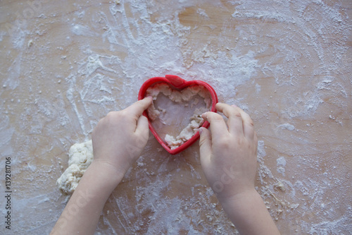 dziecięce dłonie lepiące ciastko w kształcie serca