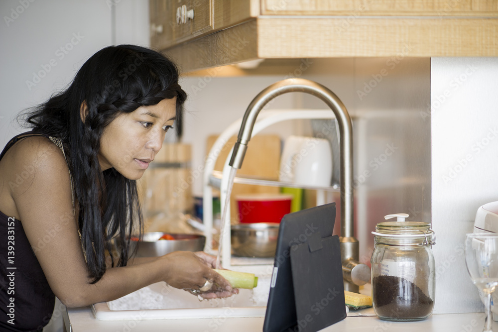 Woman using digital tablet while preparing food at home Woman using digital tablet while preparing food at home