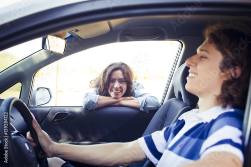 Woman looking into car window while man sitting in driver seat photo