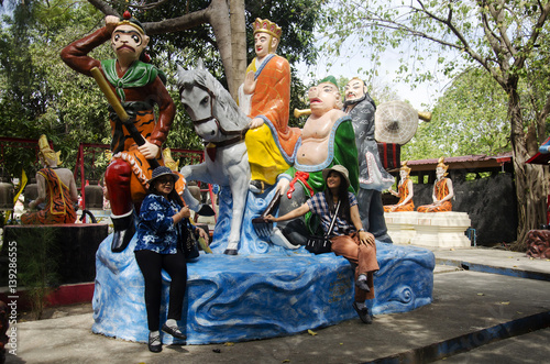 Thai woman sit and posing for take photo with Journey to the West statue