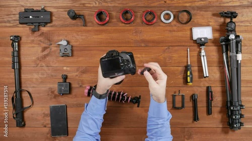 Hands male photographer puts the camera tripod flexible. Wooden table top view. Equipment for shooting on the table