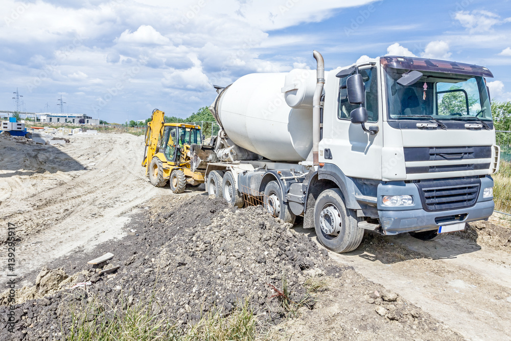 Truck mixer in process of pouring concrete into bulldozer scoop Truck mixer in process of pouring concrete into bulldozer scoop