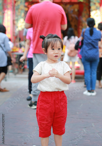 Cute little girl doing welcome expression reverence in Yaowarat Road (Bangkok chinatown) at Chinese new year, Bangkok Thailand.