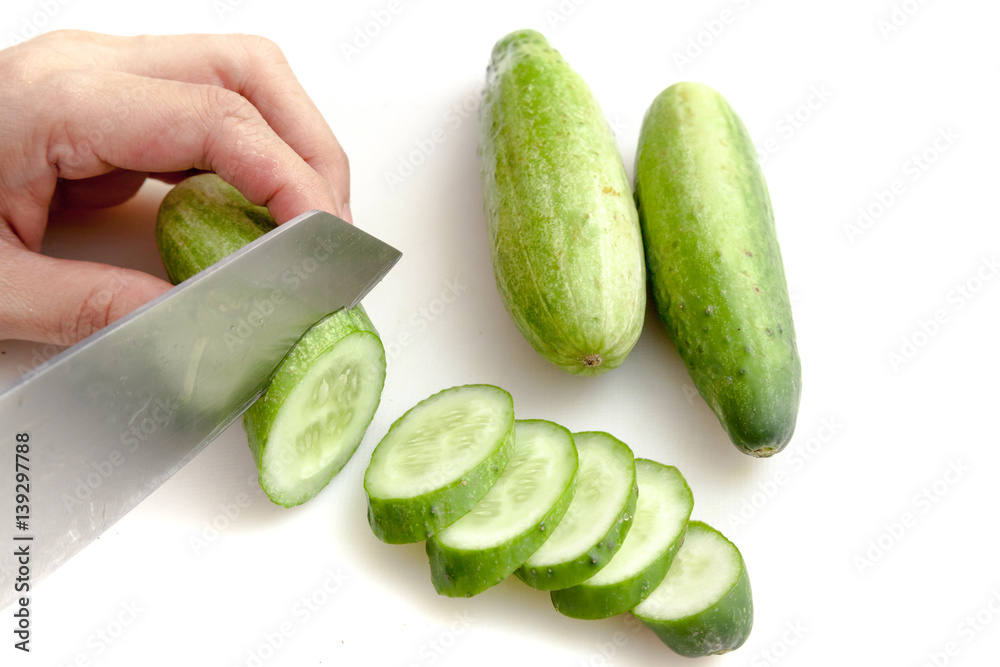 Cutting cucumbers into small slices on white background isolated