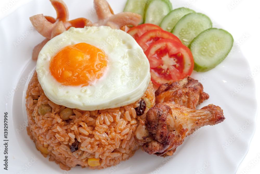 American fried rice with sausages, fried egg, fried chicken, cucumber and tomatoes,Thai style