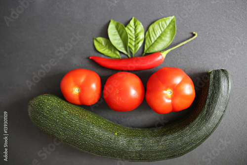 bio  concept . tomatoes,  green  zucchini, hot chilli peppers, green leaves on a black background