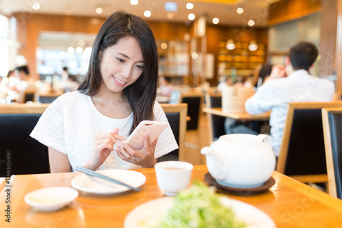 Woman use of mobile phone at chinese restaurant