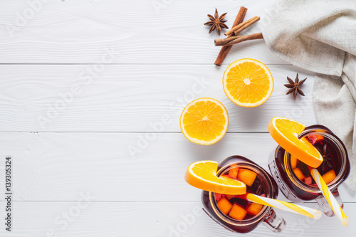 Two fruit tea in vintage glass jars with drinking straw on white wooden  background top view. Vintage mason jars with ice red tea  orange  cinnamon and star anise on white table  flat lay.  